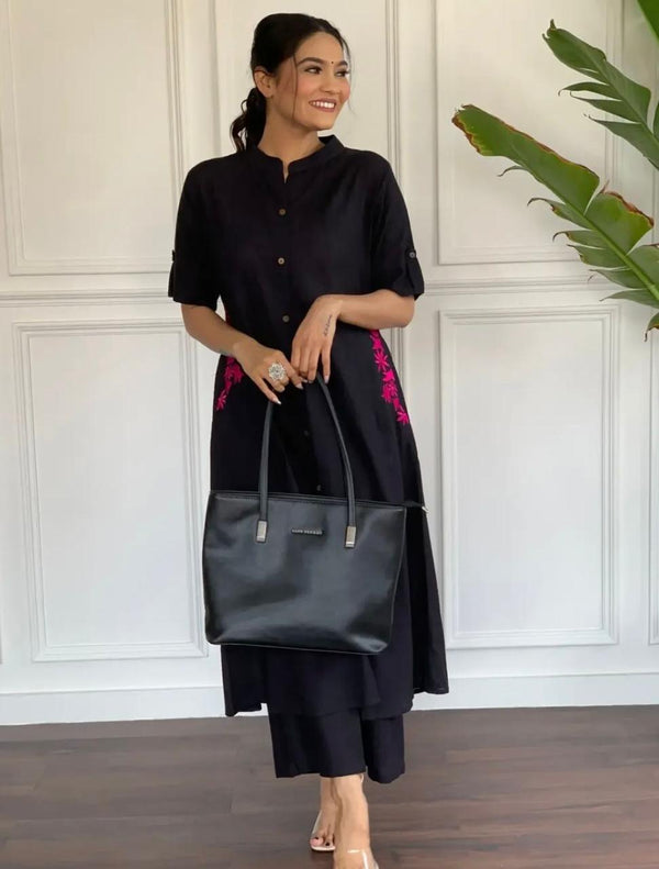 Black A-line cotton suit for women with pink embroidery paired with black pants and a black handbag