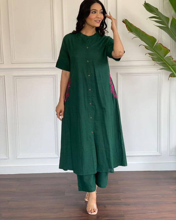 Woman wearing a dark green A-line cotton suit for women with button-down front and floral side embroidery