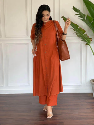 Woman wearing a rust orange A-line cotton suit for women with button-front and side embroidery