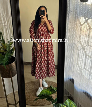 Woman wearing casual printed middy gown in maroon with white floral patterns standing in front of mirror
