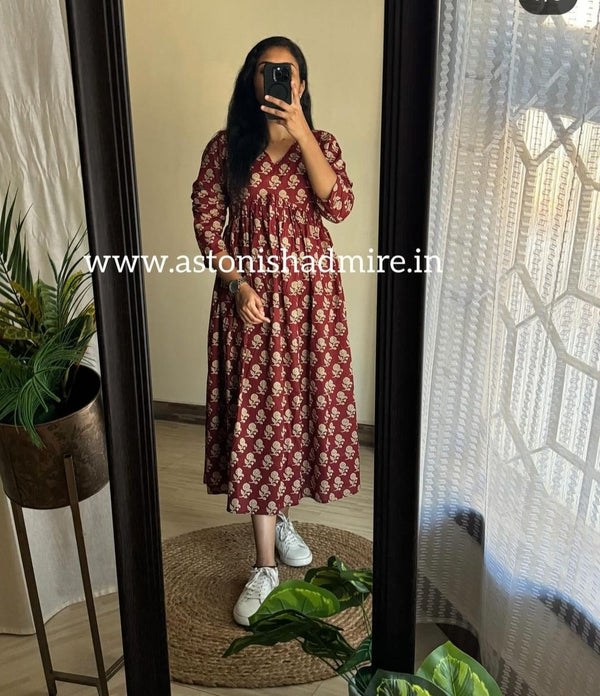 Woman wearing casual printed middy gown in maroon with white floral patterns standing in front of mirror