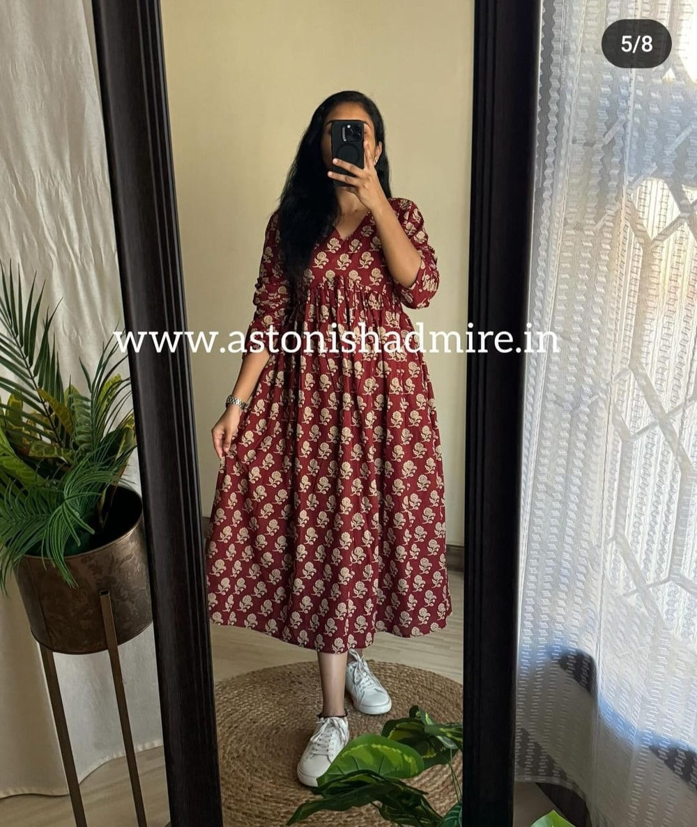 Woman wearing a casual printed middy gown in maroon floral pattern by THREAD JAIPUR standing in front of a mirror