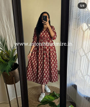 Woman wearing a casual printed middy gown in maroon floral pattern by THREAD JAIPUR standing in front of a mirror