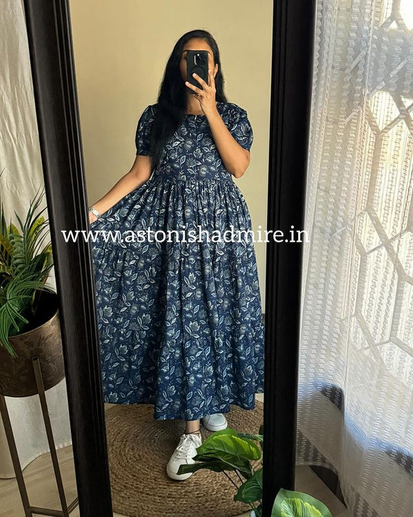 Woman wearing a blue floral maternity friendly summer dress by Cotton suit taking a mirror selfie
