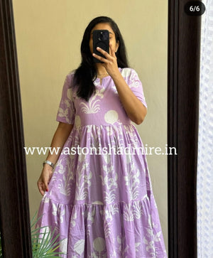 Woman wearing a purple print middy gown with white floral patterns and short sleeves