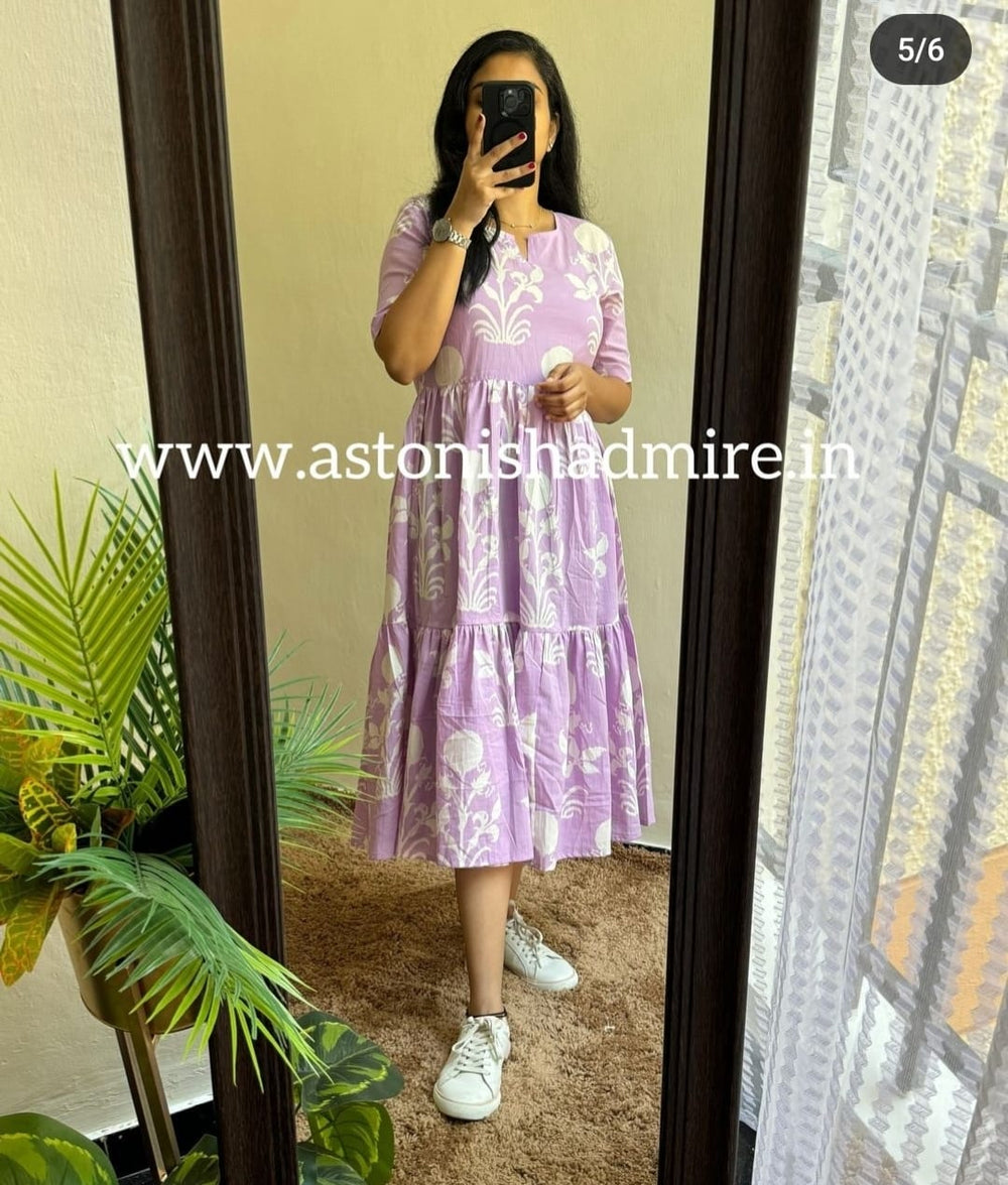Woman wearing purple print middy gown with white floral designs standing in front of mirror