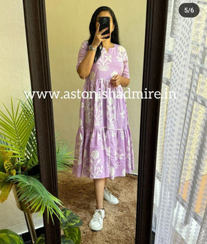 Woman wearing purple print middy gown with white floral designs standing in front of mirror