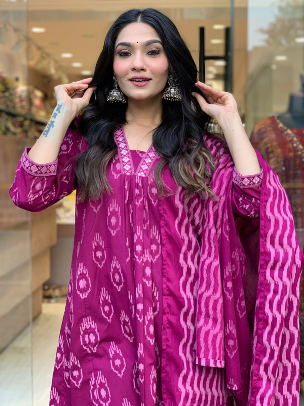 Woman wearing a magenta cotton embroidered kurta pant dupatta set with traditional patterns and silver jhumka earrings