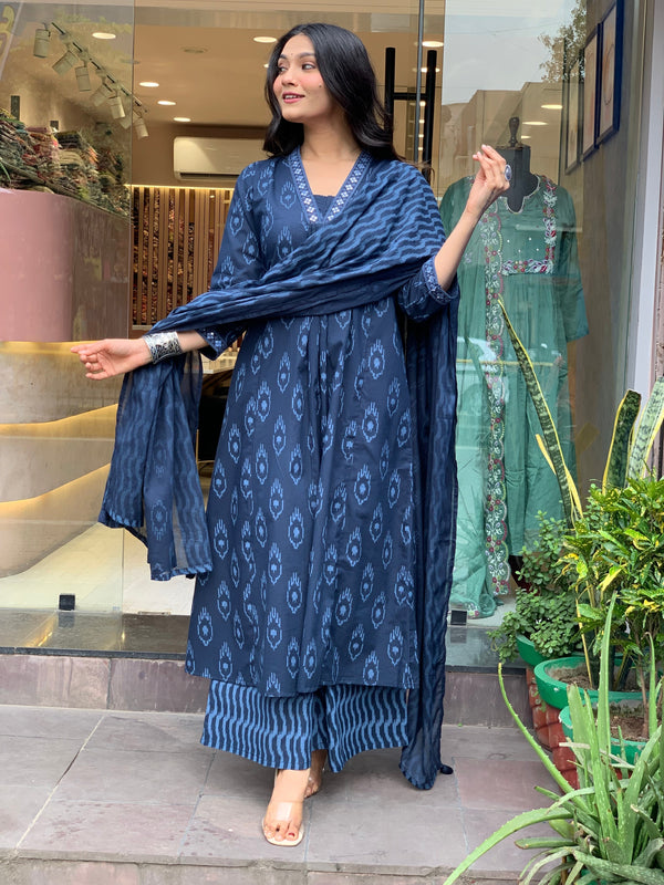 Woman wearing blue cotton embroidered kurta pant dupatta set by Cotton Suit standing outside a store