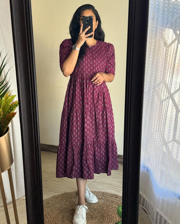 Woman wearing maroon floral printed cotton maxi dress by Cottonsuit standing in front of mirror