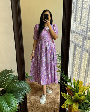 Woman wearing a purple flower print cotton maxi dress standing in front of a mirror with indoor plants