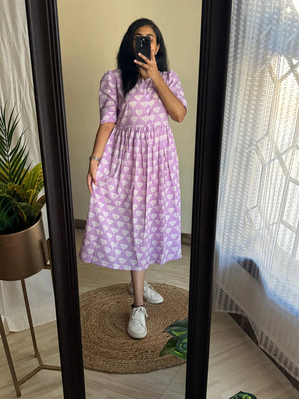 Woman wearing a purple print full flair middy gown for women standing in front of a mirror