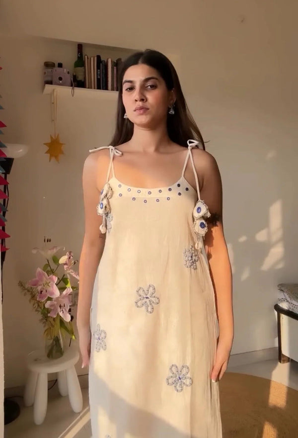 Woman wearing a light beige hand work ethnic cotton suit with floral embroidery and tie straps
