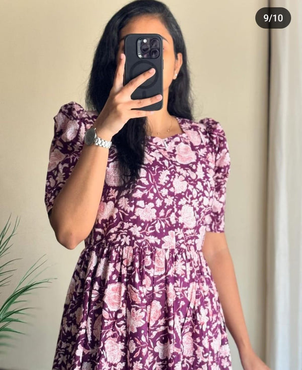 Woman wearing a purple and white floral Ikkat print gown by  Cotton Suit standing indoors