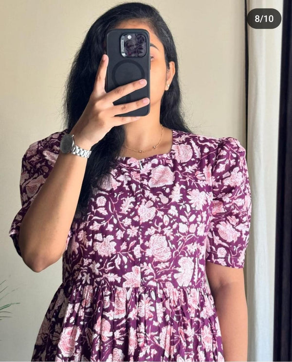 Woman wearing purple and pink floral Ikkat print gown with puff sleeves taking a mirror selfie