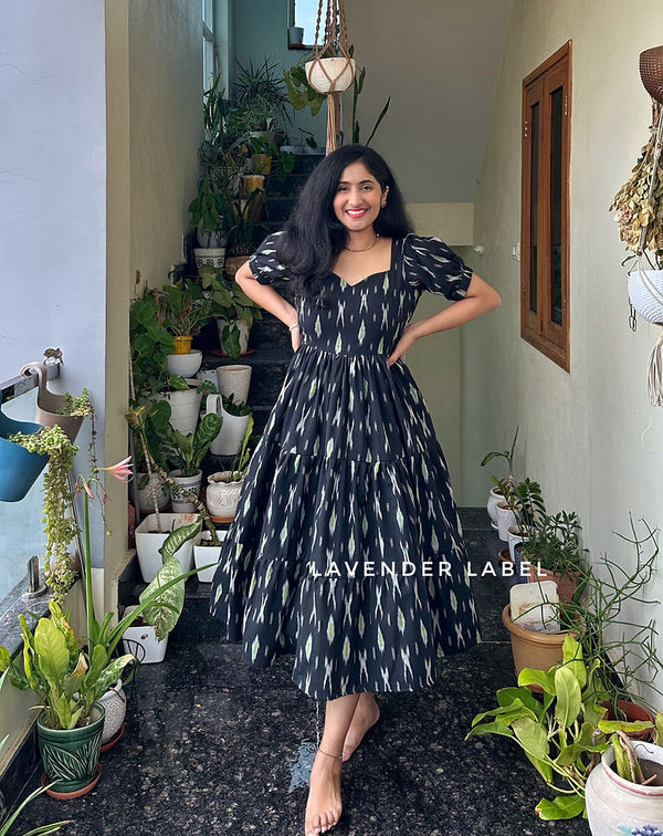 Smiling woman wearing casual cotton midi with sweetheart neckline standing among green potted plants indoors