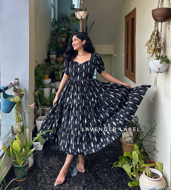 Woman wearing casual cotton midi with sweetheart neckline black patterned dress standing barefoot indoors