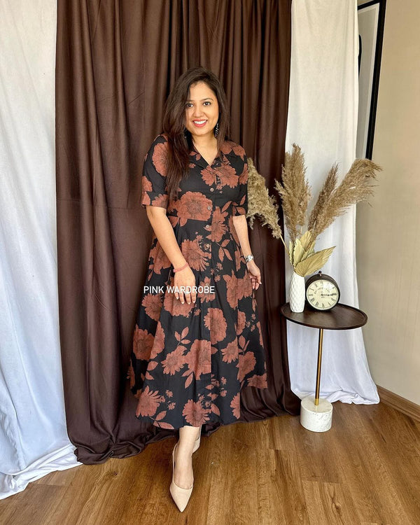 Woman wearing a Cottonsuit casual a-line cotton dress with floral print standing indoors near a side table with decor