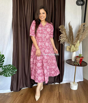 Woman wearing a pink floral cotton dress for women standing indoors with decorative plants