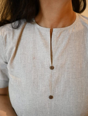 Close-up of a women's khadi cotton outfit in light gray with a round neckline and two brown buttons