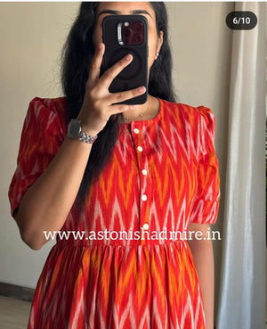 Woman wearing a rust orange ikkat middy gown with puff sleeves and button details front