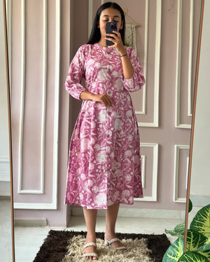 Woman wearing a pink floral summer daily wear dress for women standing in front of a mirror