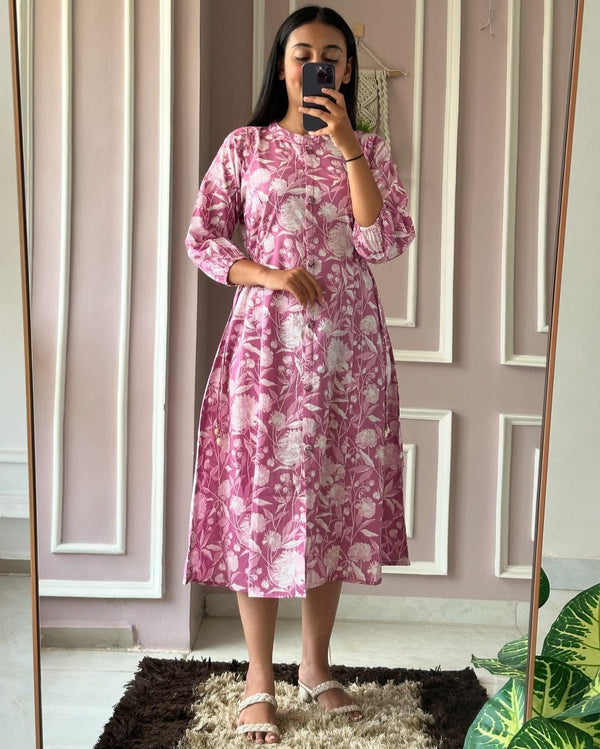 Woman wearing a pink floral summer daily wear dress for women standing in front of a mirror