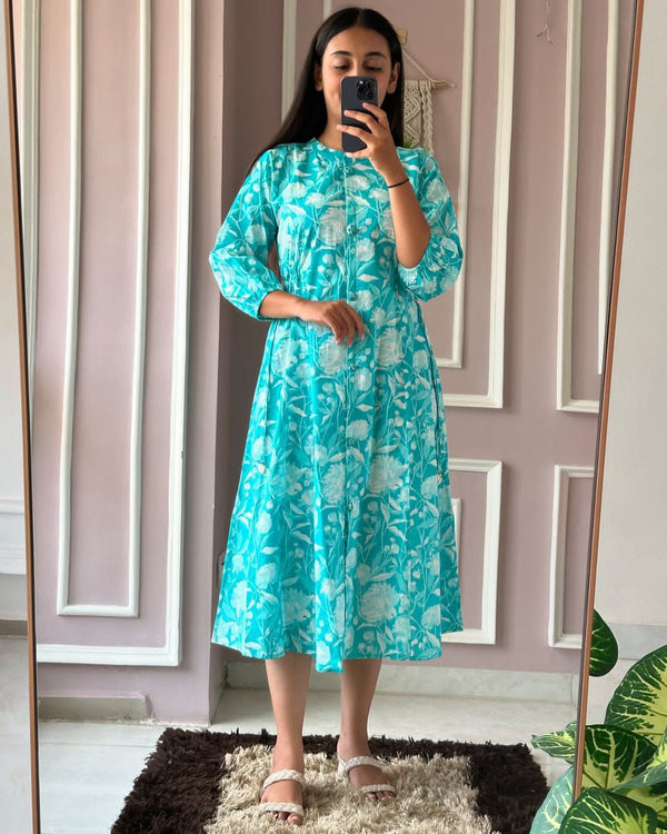Woman wearing a blue floral summer daily wear dress for women by Cotton Suit standing in front of a mirror