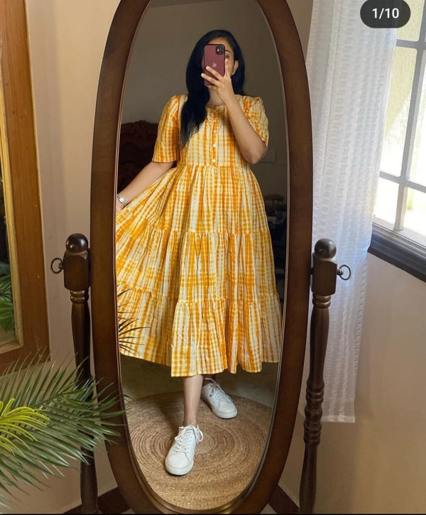 Woman wearing yellow summer ikkat midi gown for women with buttons and puff sleeves standing in front of a mirror