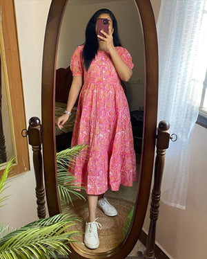 Woman wearing a pink lehriya print casual dress for women with short puff sleeves and white sneakers