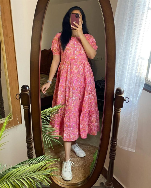 Woman wearing a pink lehriya print casual dress for women with short puff sleeves and white sneakers