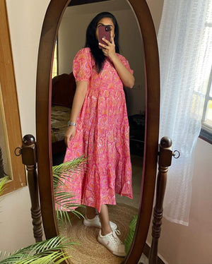 Woman wearing pink lehriya print casual dress for women with puff sleeves and white sneakers