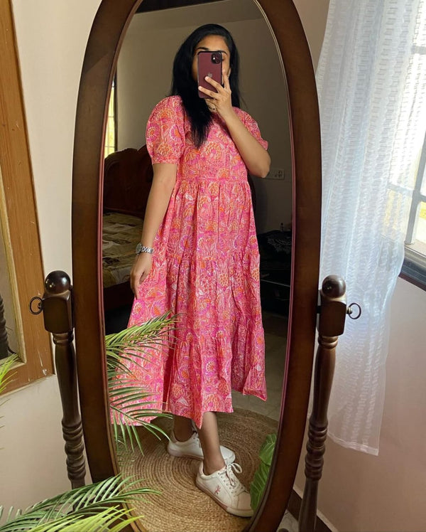 Woman wearing pink lehriya print casual dress for women with puff sleeves and white sneakers