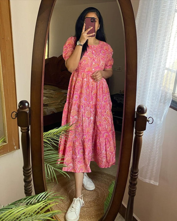 Woman wearing pink lehriya print casual dress for women taking a mirror selfie with white sneakers