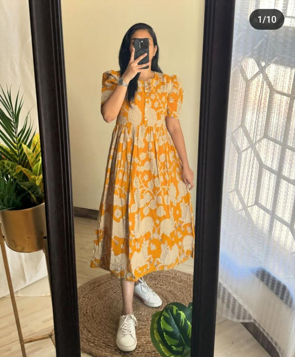 Woman wearing a vibrant orange and beige floral women's midi cotton gown standing in front of a mirror