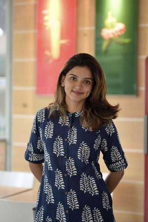 Woman wearing a navy blue women's summer cotton co-ord suit with white leaf patterns indoors