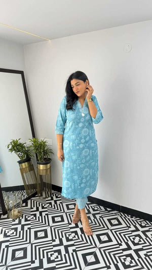Woman wearing blue printed kurta standing on black and white patterned floor indoors