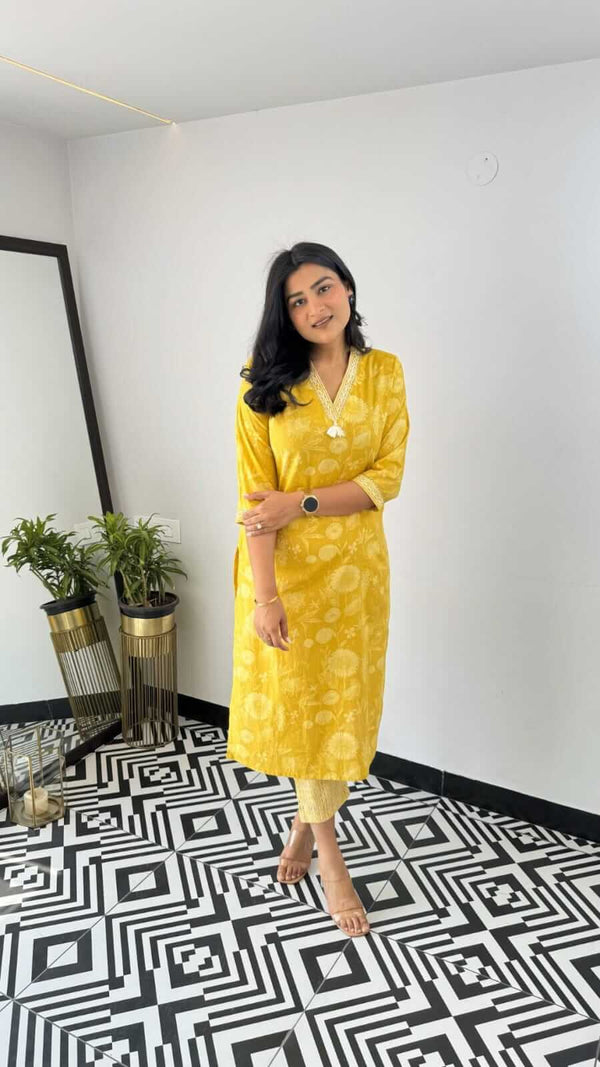 Woman wearing yellow and pink office wear kurta standing on patterned floor in minimalist room