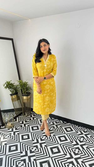 Woman wearing a yellow and pink office wear kurta standing indoors with geometric black and white floor