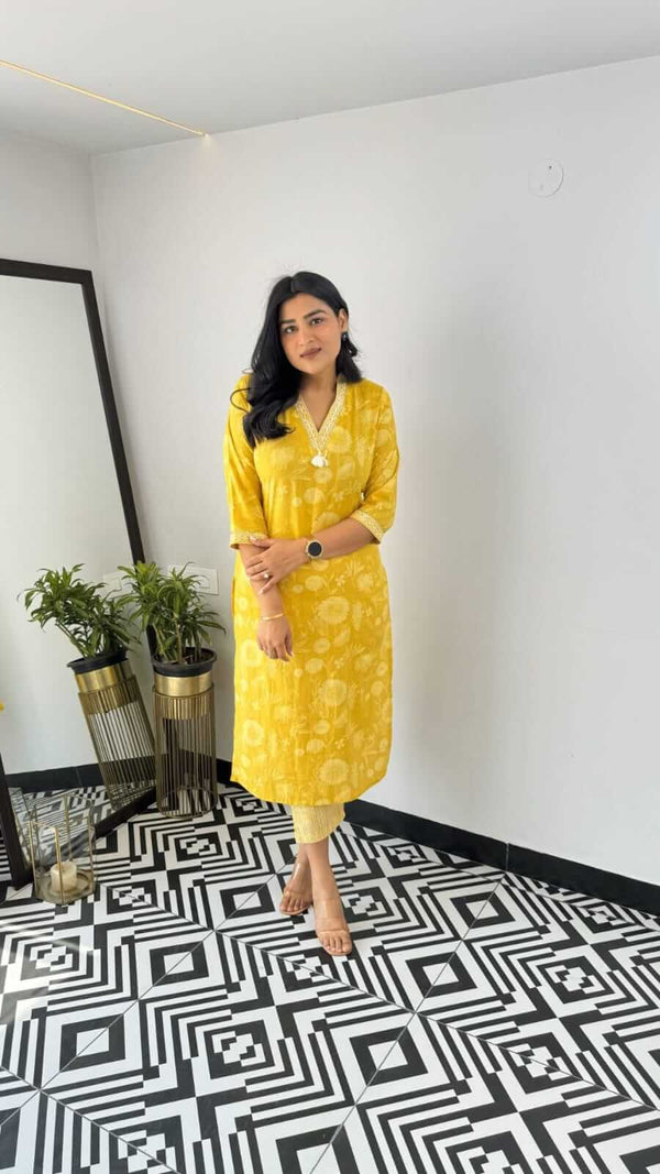 Woman wearing a yellow and pink office wear kurta standing indoors with geometric black and white floor
