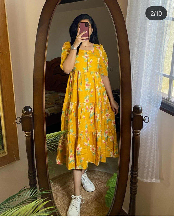 Woman wearing yellow casual kurti with sleeves and floral print standing in front of a full-length mirror